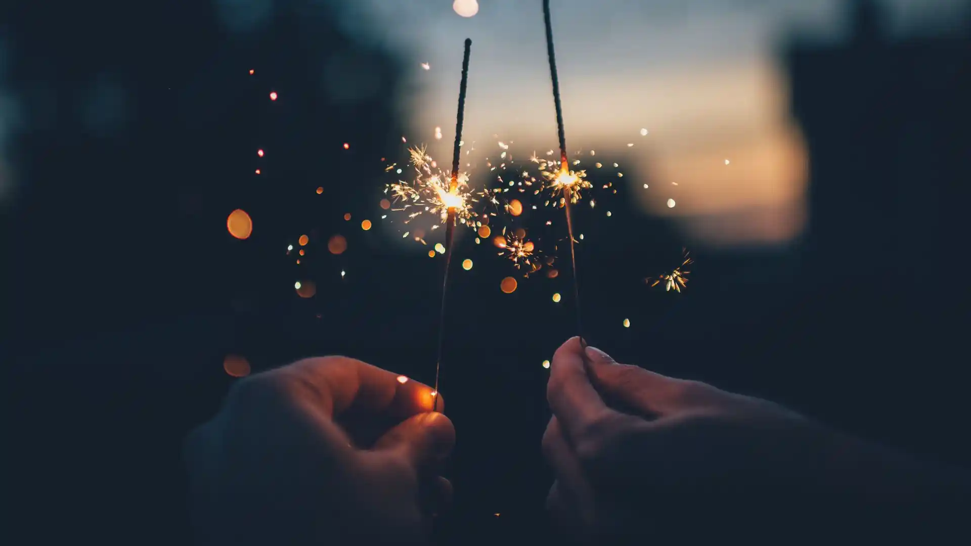 background image of two people holding sparkles in the sunset