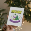 A nonbinary-themed Christmas card with a cute polar bear, adorned in a bright scarf, surrounded by snowflakes and joy.