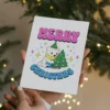 A playful card showing a cartoon bear next to a Christmas tree, designed for pansexual holiday celebrations.