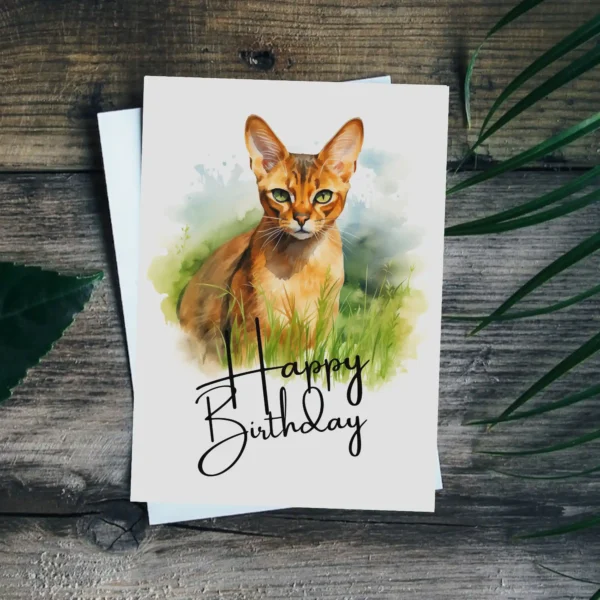 Watercolor illustration of an Abyssinian cat on a birthday card, set in nature, with a joyful "Happy Birthday" message.