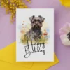 Watercolor illustration of a cheerful Affenpinscher on a birthday card, surrounded by nature and a "Happy Birthday" message.
