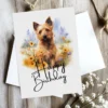 Charming birthday card showcasing a Australian Terrier in a serene setting, complete with a "Happy Birthday" message.