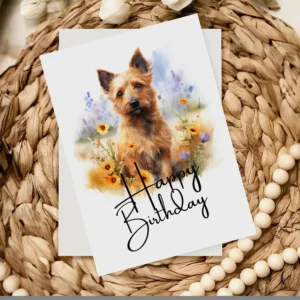 Delightful watercolor birthday card of a Australian Terrier in a natural backdrop, adorned with a "Happy Birthday" note.
