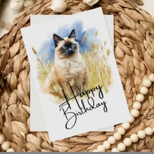 Charming watercolor illustration of a Balinese cat on a birthday card, set in nature with a "Happy Birthday" note.