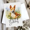 Watercolor birthday card of a cheerful Basenji dog in a natural environment, complete with a "Happy Birthday" message.