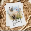 Watercolor illustration of a Birman cat in nature, featured on a birthday card with a "Happy Birthday" message.