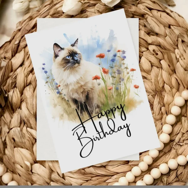 Watercolor illustration of a Birman cat in nature, featured on a birthday card with a "Happy Birthday" message.