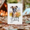 Charming watercolor card of a boxer dog in nature, celebrating with a "Happy Birthday" message for dog lovers.