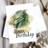 Colorful birthday card showing a dragon head and "Happy Birthday" on a cheerful golden cloud background.