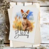 Printable birthday card with a watercolor drawing of a Cornish Rex cat in a natural scene, adorned with "Happy Birthday" text.