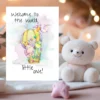 A delightful card illustrating a cartoon bird and balloon, with the welcoming message, "Welcome to the world, little one!" in watercolor.