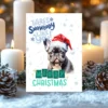Holiday card featuring a French Bulldog in red Santa hat and winter scene