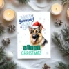 Festive German Shepherd in Santa hat and snow scene for a unique Christmas greeting