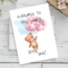 Adorable new baby card with a teddy bear, pink balloons, and the message, "Welcome to the world, little one!" in watercolor.
