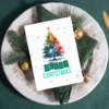 Colorful watercolor Christmas tree with “Merry Christmas” on a soft snow-filled background