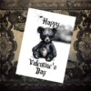A printable Valentine's Day card with a black bear on a marble table, blending Gothic style with a touch of creepiness.