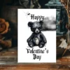 A spooky Gothic Valentine's card showing a black bear on a marble table, perfect for those who love unique designs.