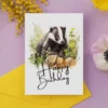Charming watercolor badger birthday card, showcasing a natural scene and a festive "Happy Birthday" greeting.