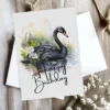Charming birthday card featuring a black swan watercolor design in nature, adorned with a bright "Happy Birthday" message.