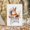 Cheerful birthday card with a watercolor squirrel in a natural winter setting, adorned with a "Happy Birthday" message.
