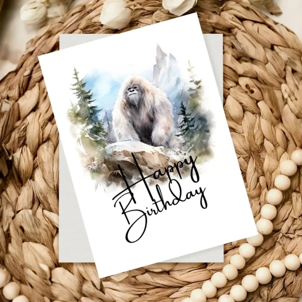 Whimsical Yeti birthday card in a natural landscape, showcasing a colorful "Happy Birthday" message in watercolor style.